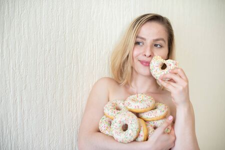 131568191-mujer-joven-desnuda-comiendo-donas-retrato-de-una-mujer-atractiva-con-una-montaña-de...jpg