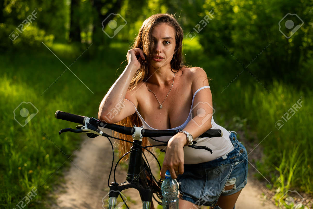171161872-joven-mujer-sexy-con-grandes-pechos-monta-una-bicicleta-en-el-bosque-en-un-caluroso-...jpg